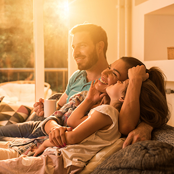 Family smiling on their couch.